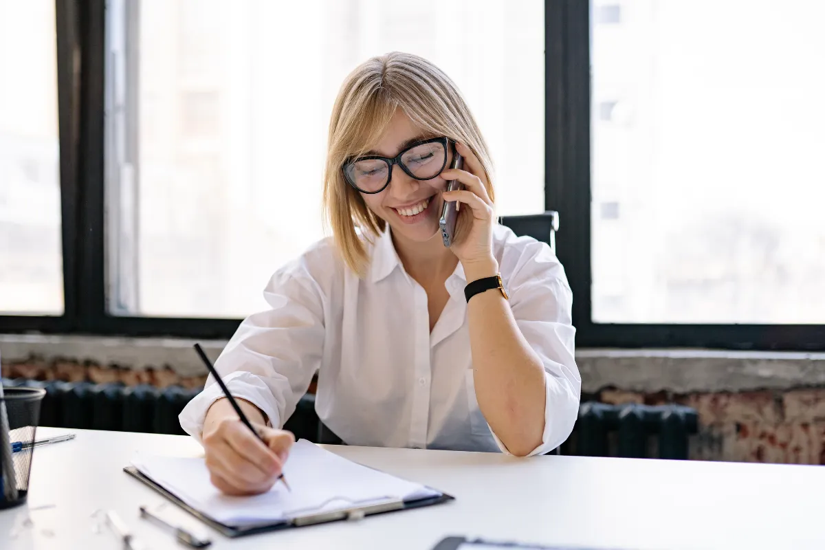 Kvinne som snakker i telefon og noterer